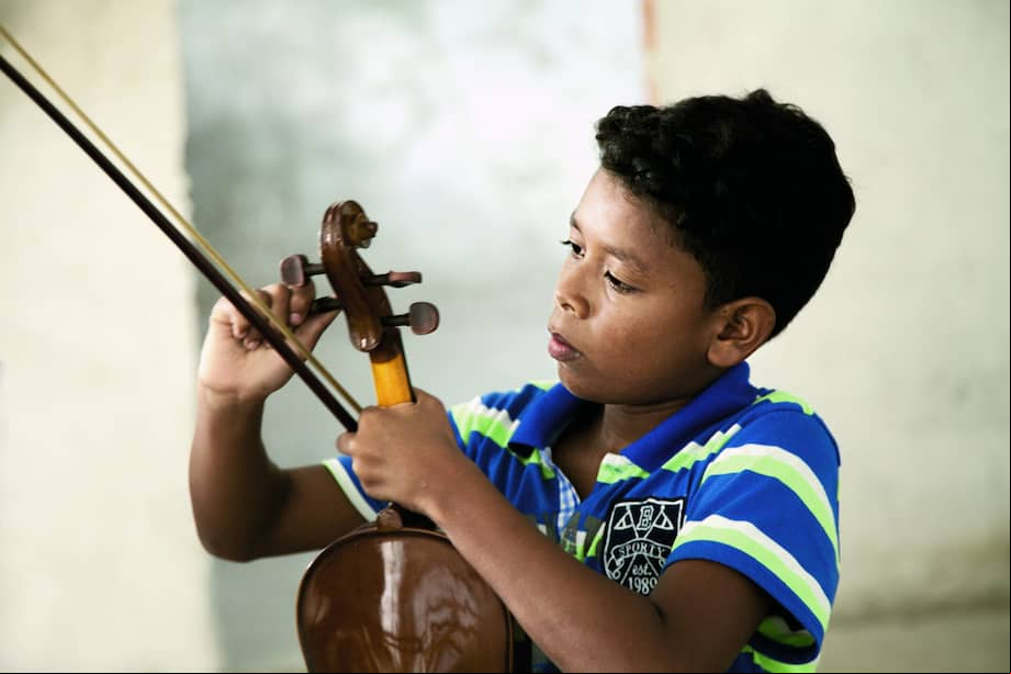 Un beneficiario de los programas de Batuta en Puerto Asís, Putumayo, ajusta su instrumento. Creada en 1991, Batuta ofrece formación musical colectiva con enfoque de inclusión y equidad.