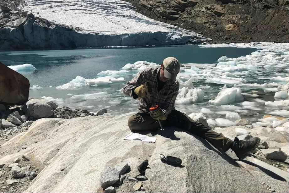 Un científico toma una muestra de roca del glaciar Queshque en la cordillera de los Andes en Perú.