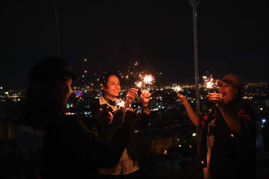Tres mujeres con luces durante la celebración de la milenaria fiesta zoroástrica del 'Chaharshanbe Suri'.